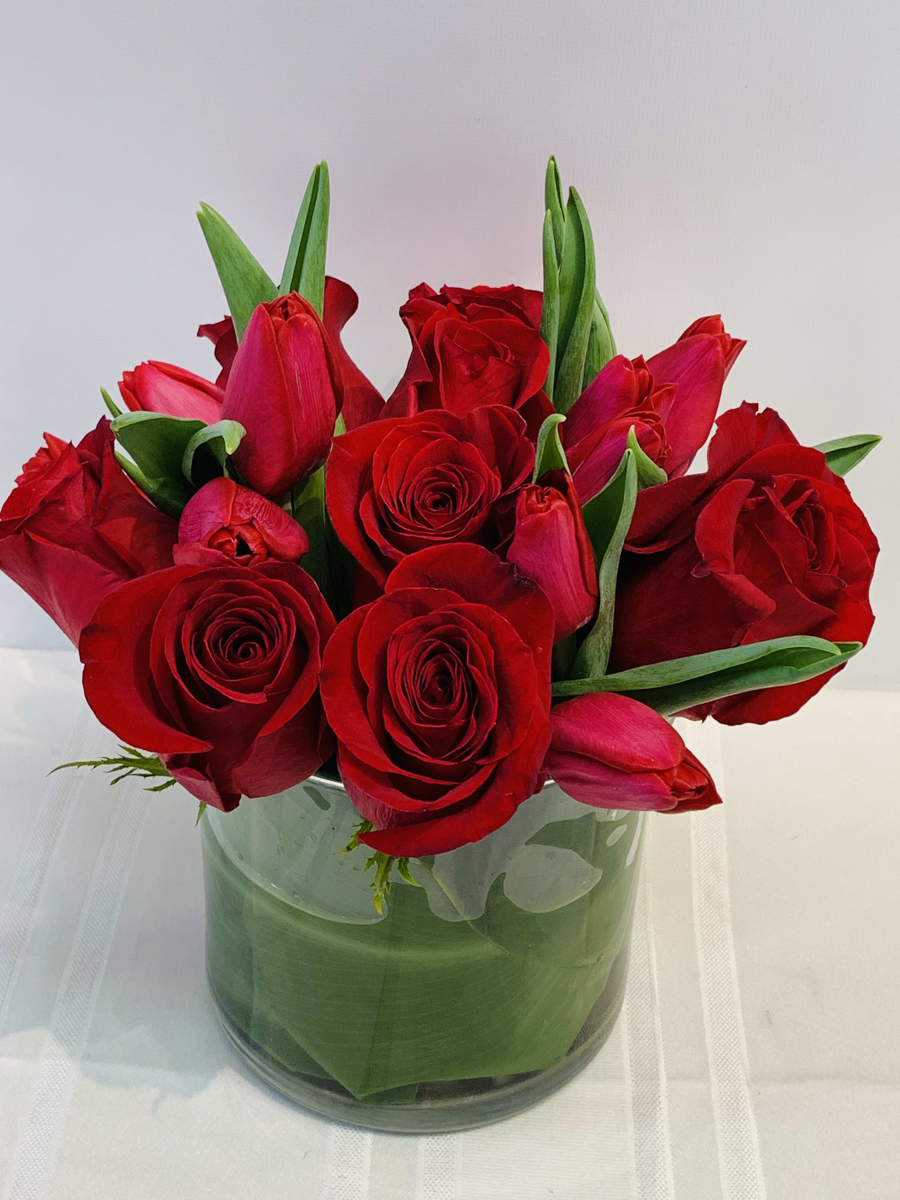 Large red roses and red tulips - W662   - 10 Red Tulips and 8 Large Red Roses arranged in green leafed cylinder glass vase.  Pick this all red floral arrangement to send a Love message to person who you love.  Dimension approximately: 9"x7"  W662