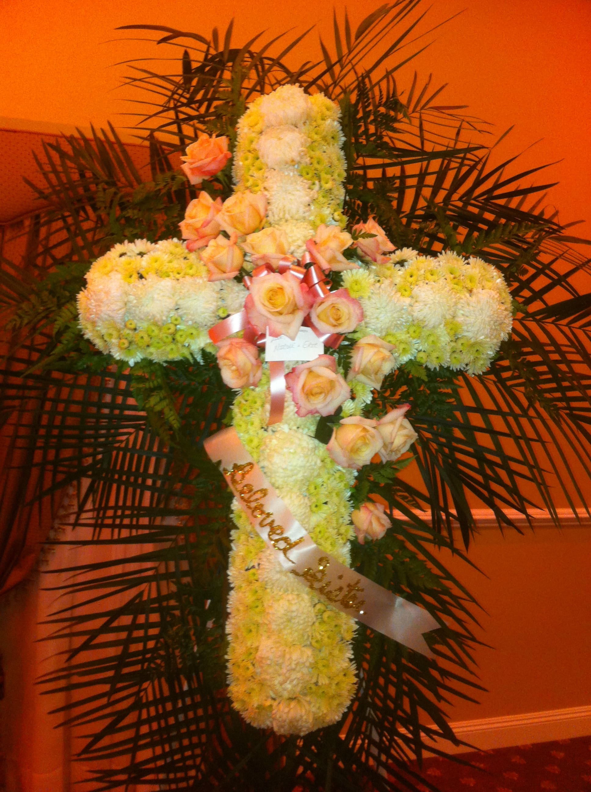 Cross-shaped floral tribute with white chrysanthemums and peach roses