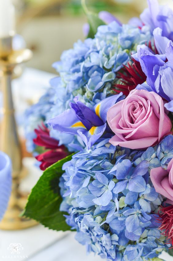 Close-up bouquet of blue hydrangeas, pink roses, and purple irises