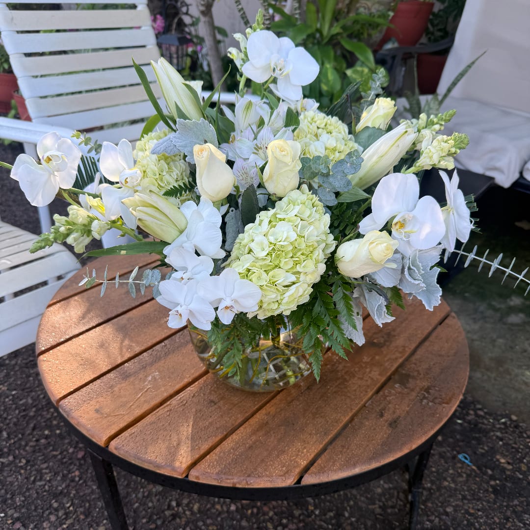 White floral arrangement in a clear glass vase on a wooden table