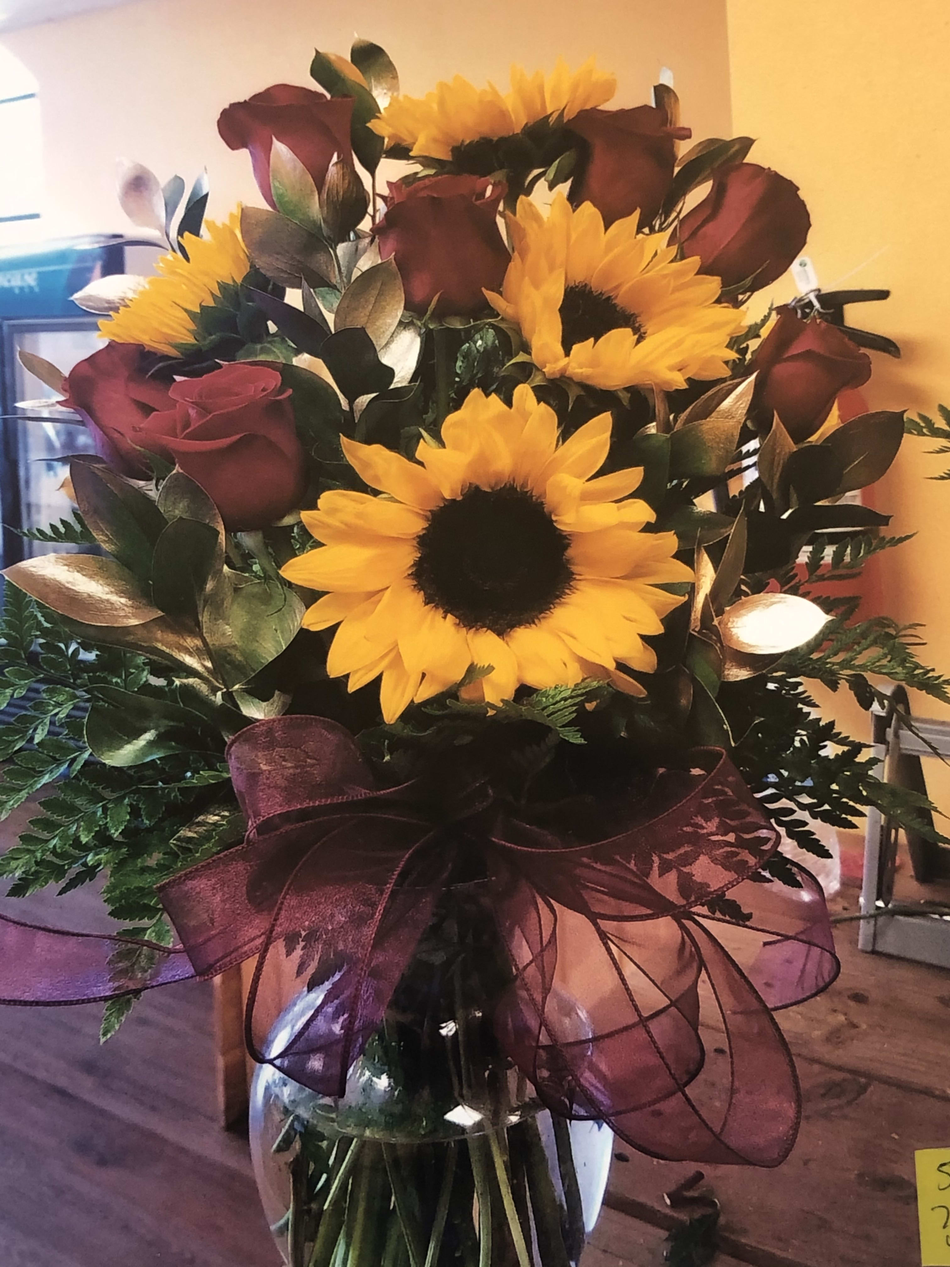 Bouquet of yellow sunflowers and burgundy roses in a glass vase
