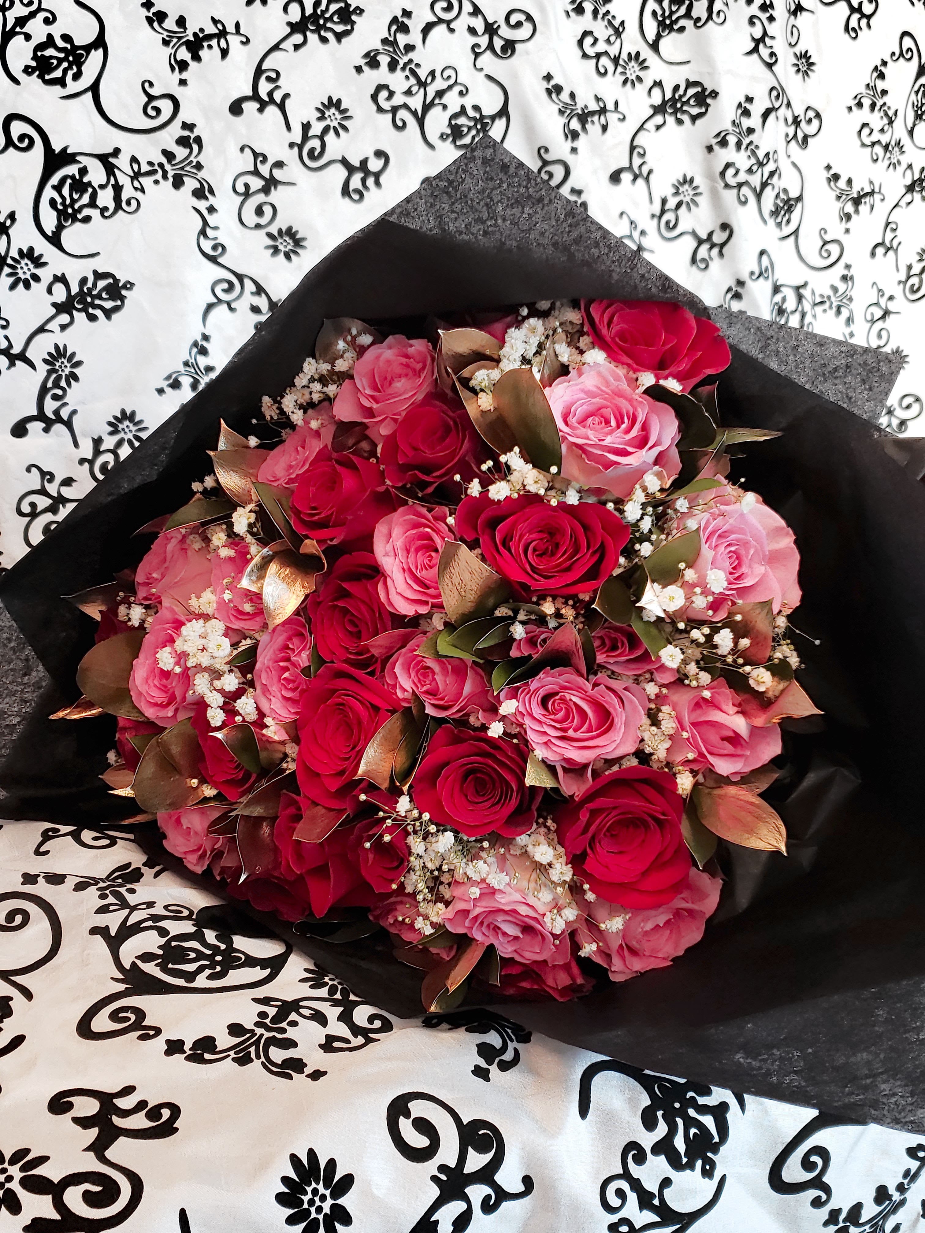 Bouquet of pink and red roses wrapped in black paper