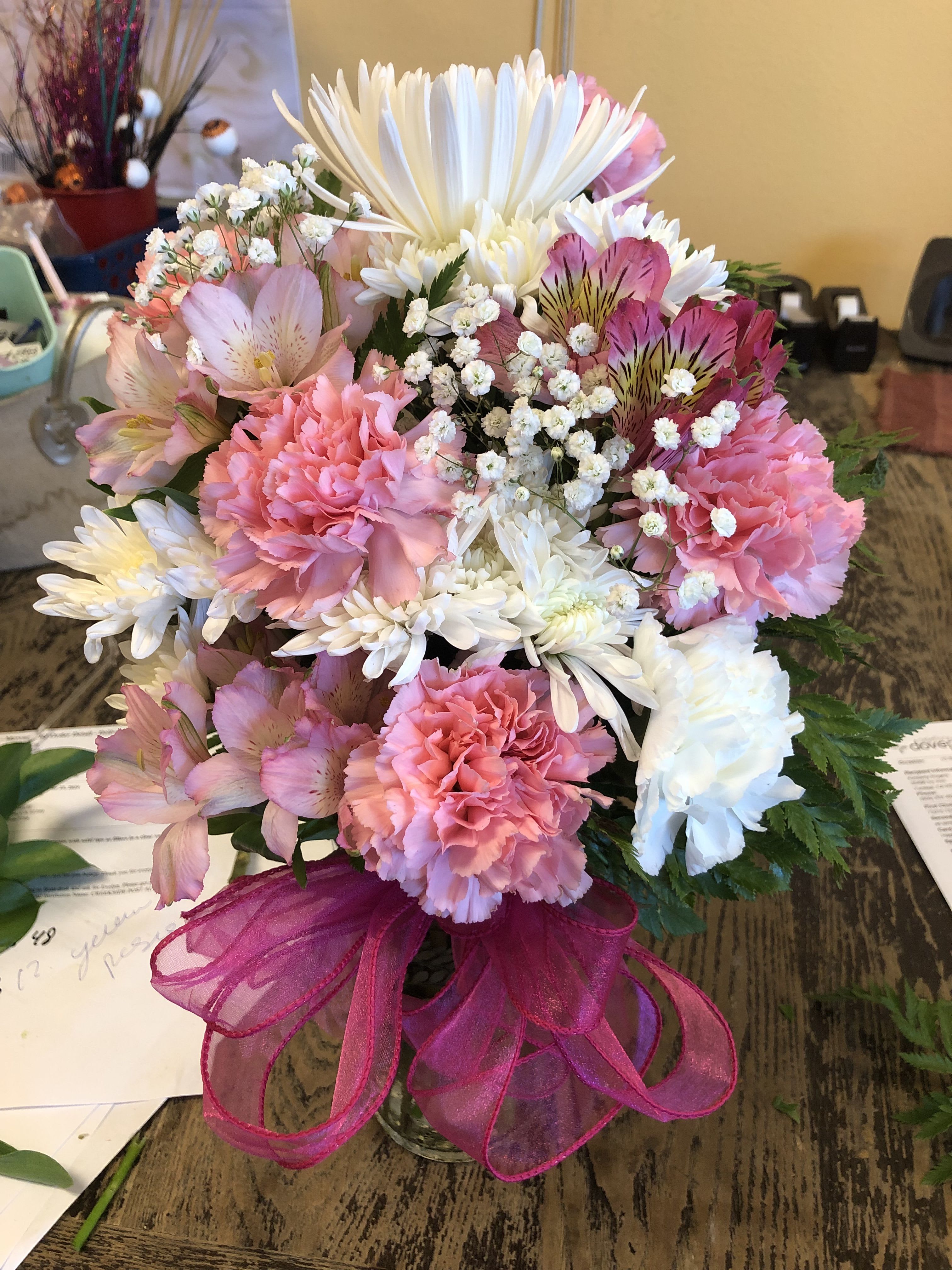 Pink and white mixed bouquet in a glass vase with a magenta ribbon