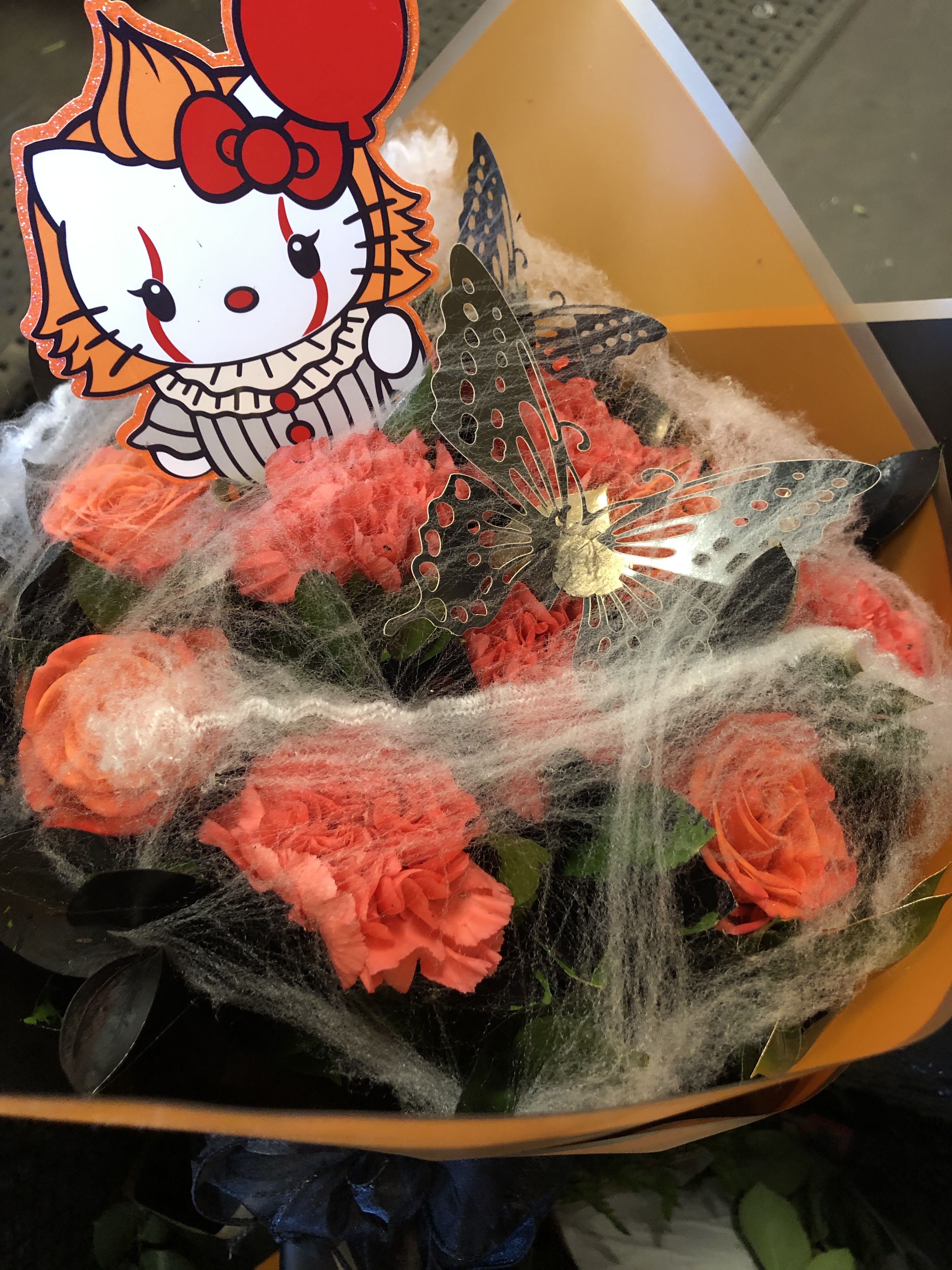 IT CLOWN WRAPPED - 6 Orange Roses, 9 Orange Carnation with Gold and Black Ruscus.   IT CLOWN CUT OFF SHOWN in the picture (ITS ABOUT 5 INCHES TALL) and black butterflies and spider webs all wrapped in orange and black Korean paper.  