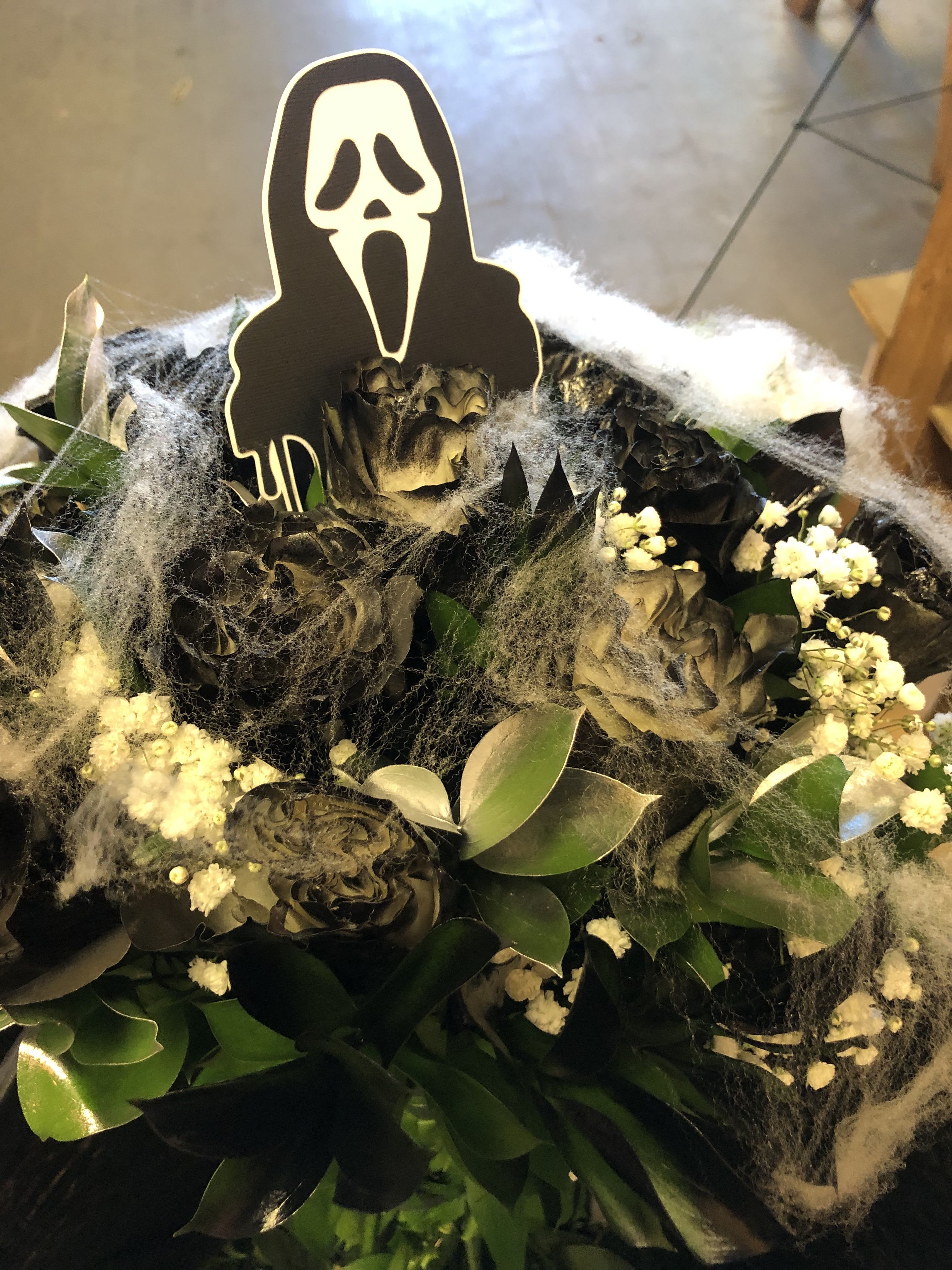 HALLOWEEN SCREAM WRAP  - SCREAM PAPER CUT OFF ( ABOUT 5 INCHES TALL) ALSO INCLUDED IS BLACK SPRAY PAINTED ROSES WITH SILVER AND BLACK RUSCUS.  SPIDER WEBS AND BUTTERFLIES INCLUDED STANDARD SIZE INCLUDES 12 ROSES DELUX SIZE INCLUDES 18 ROSES PREMIUM SIZE INCLUDES 24 ROSES (NOTE YOU CAN SUBSTITUTE THE ROSES TO ANY COLOR) ADD THIS REQUEST UNDER SPECIAL INSTRUCTIONS OR CALL US AT 9513791222