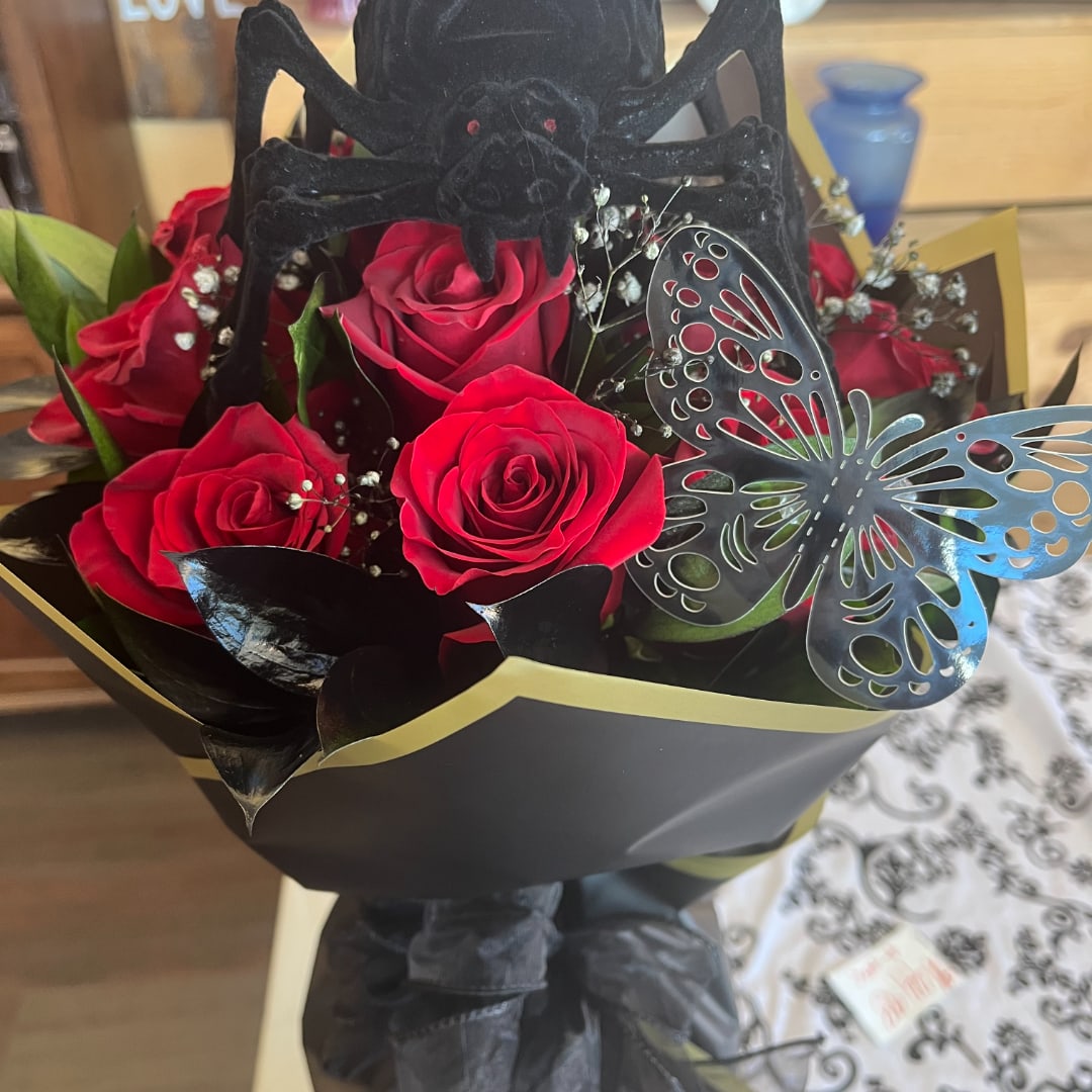 Bouquet of red roses with a black spider decoration and butterfly pick