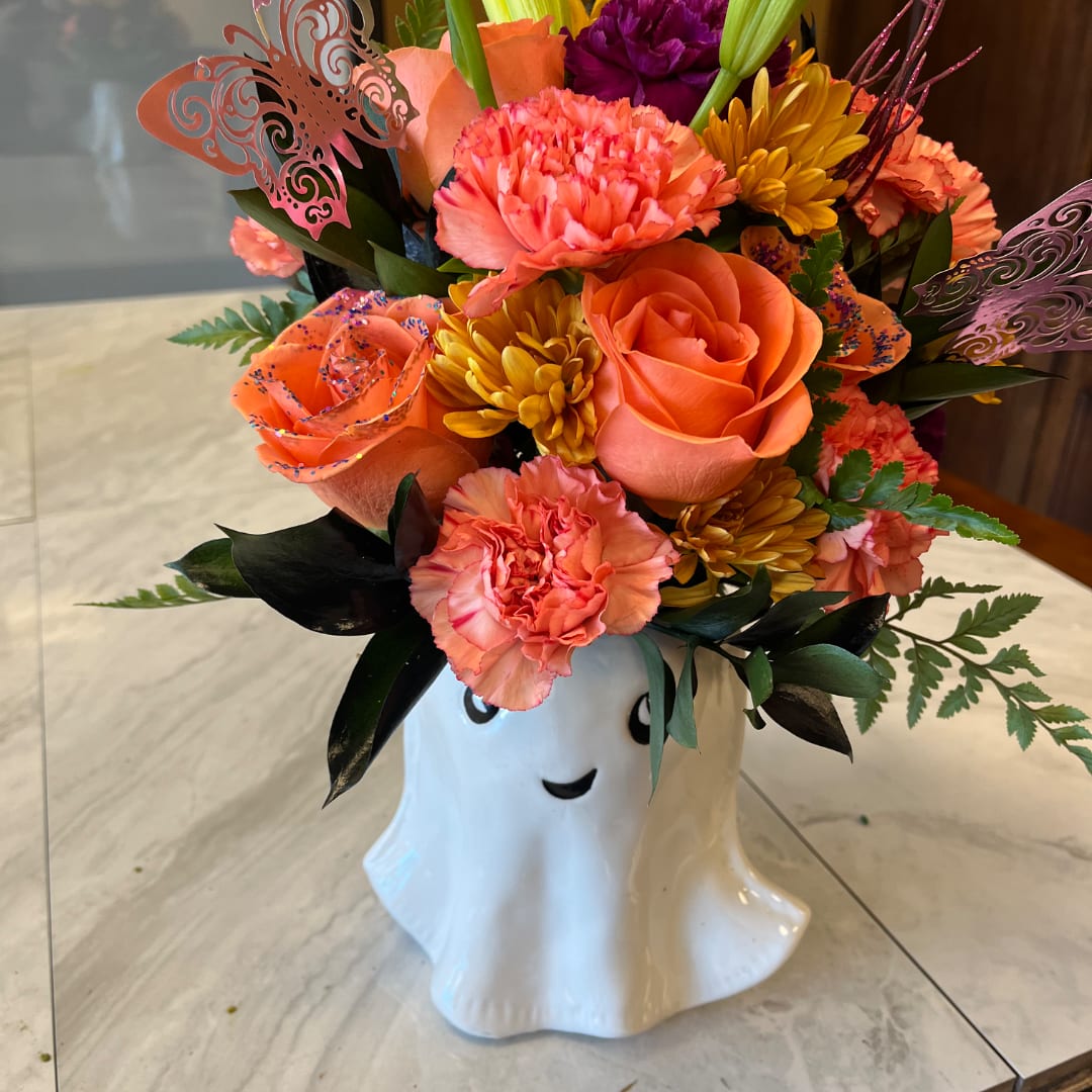 Orange and pink floral arrangement in a white ghost vase