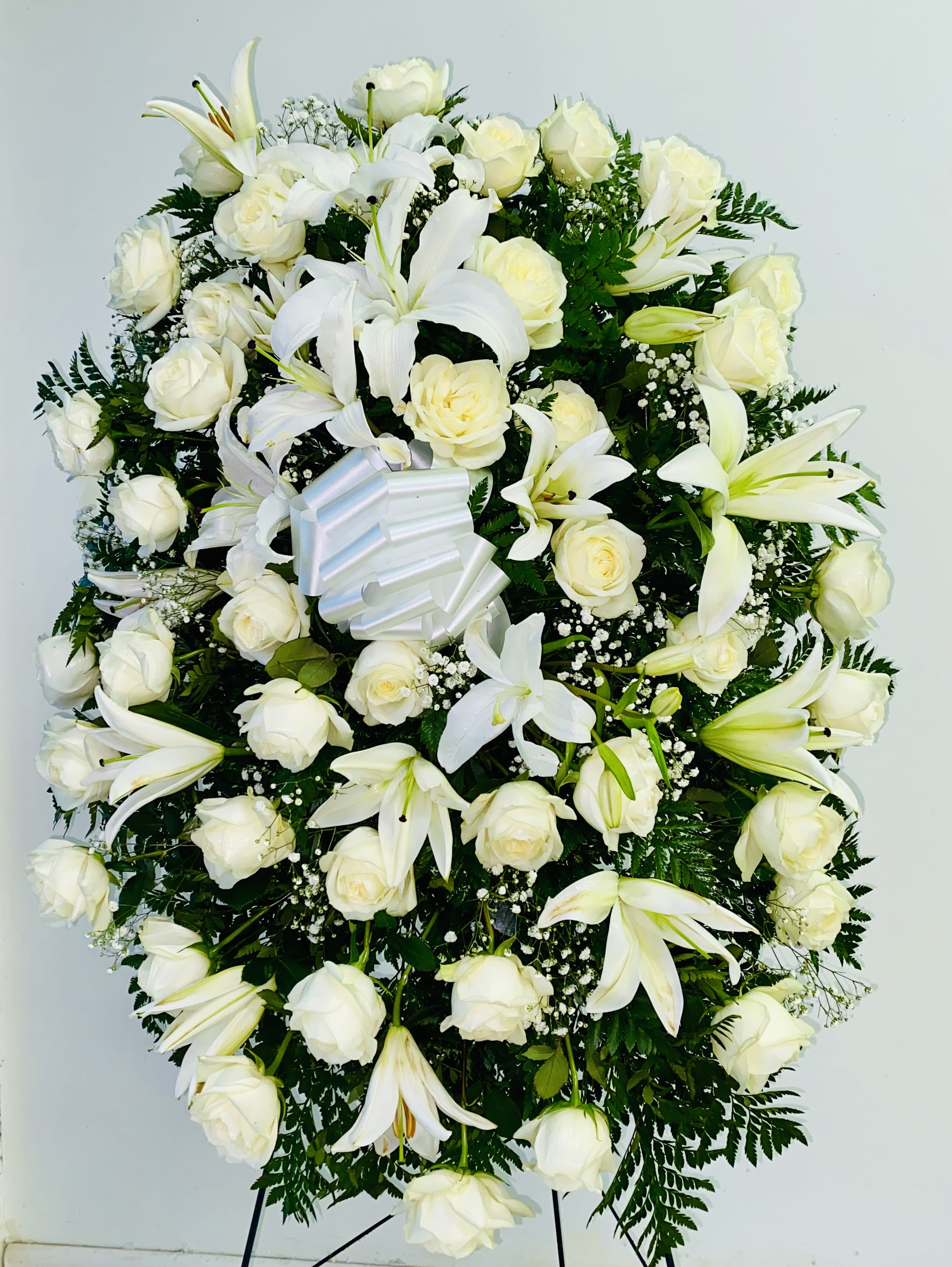 White rose and lily standing spray with a ribbon bow