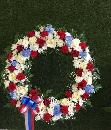 Circular floral wreath with red, white, and blue flowers on a stand