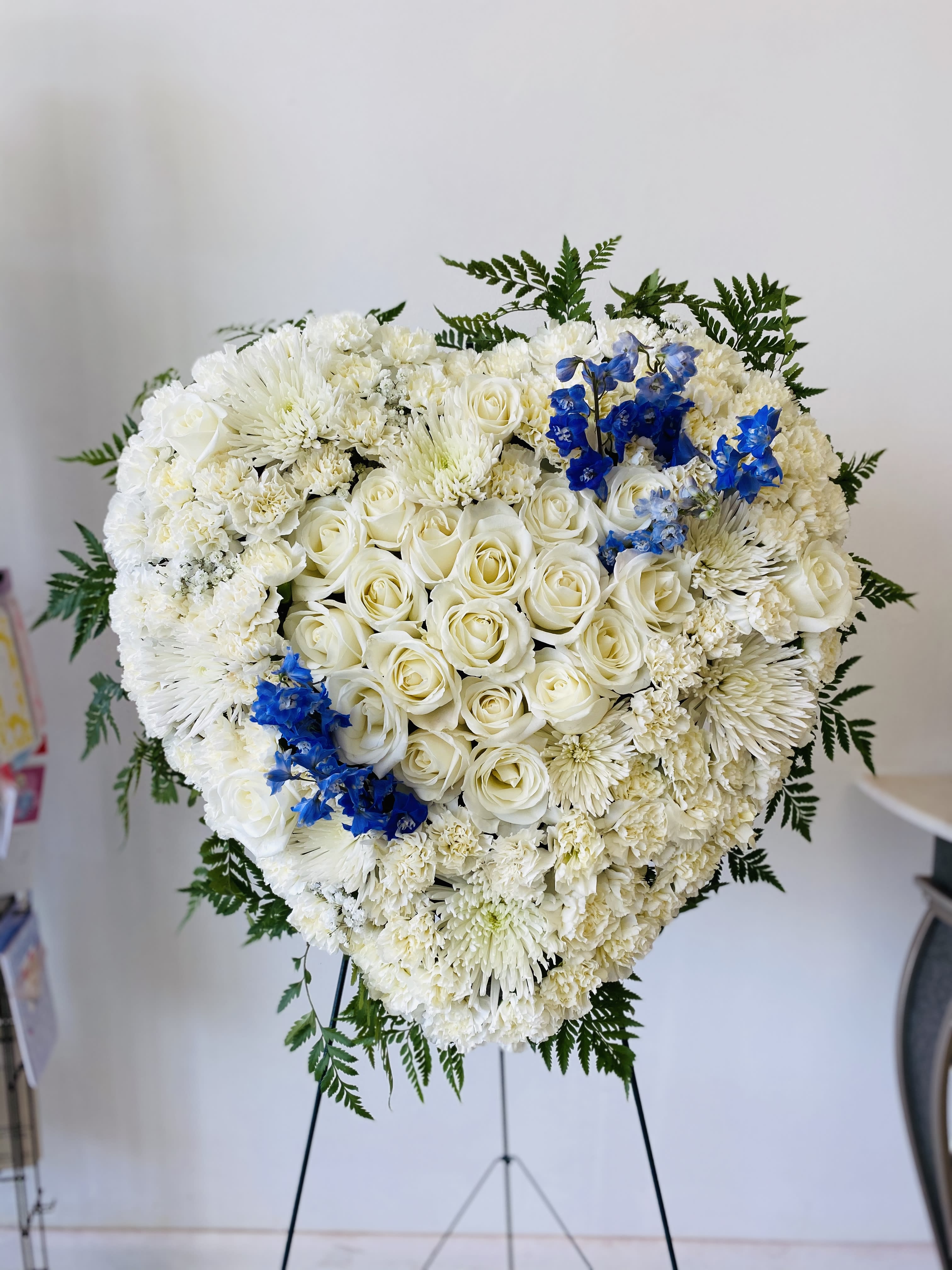 Heart-shaped white floral standing arrangement with blue accents