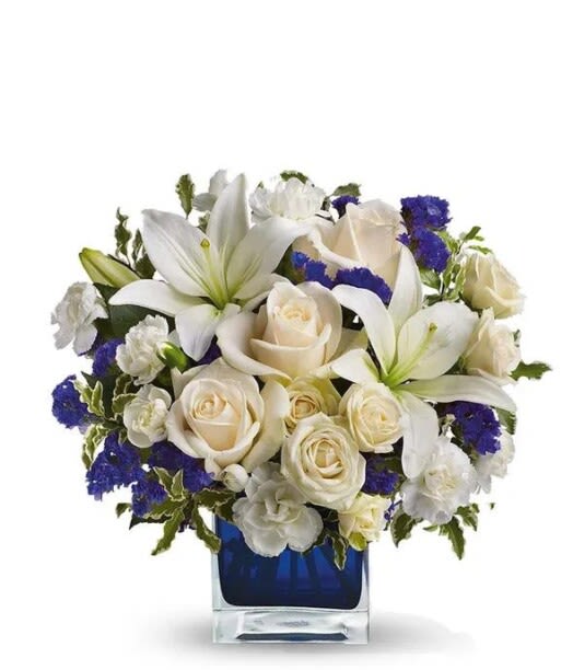 White lilies and cream roses arranged in a blue glass vase
