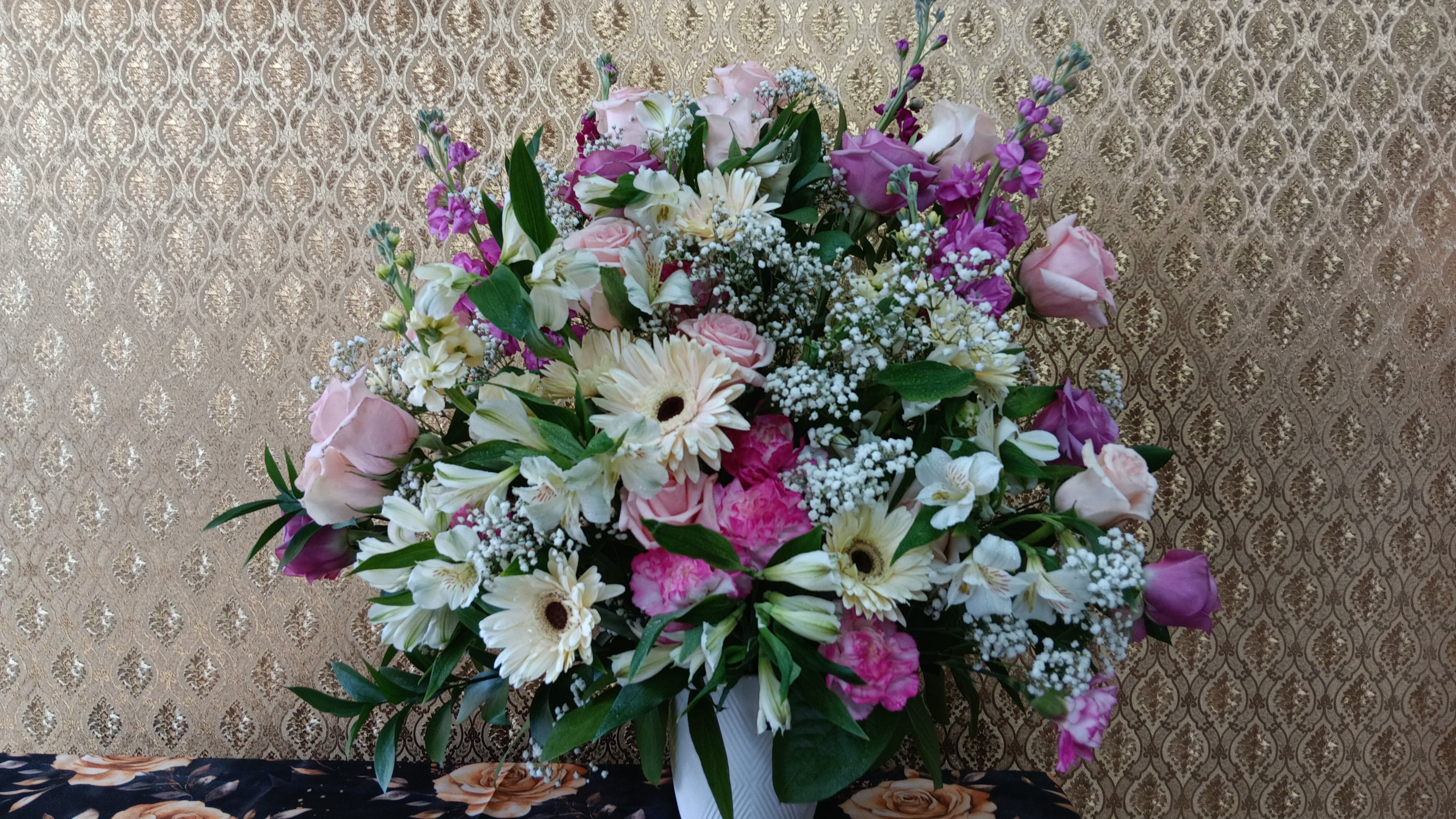 Large mixed bouquet of pink, white, and purple flowers in a white vase