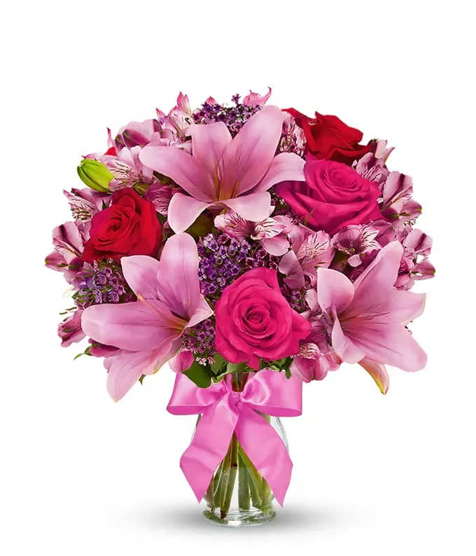 Rose &amp; Lily Celebration - Send stunning flowers to celebrate any occasion! With classic floral colors including red roses and pink lilies, the Rose and Lily Joy is a wonderful gift to send to a friend or family member for a birthday, get well or anniversary. The flowers are arranged by hand at a local florist shop. The floral artist creates the Rose and Lily bouquet with red roses, pink roses, pink lilies, pink alstroemeria and purple waxflower. Paired with the flowers is a keepsake clear vase that is wrapped in a decorative ribbon.    Includes: • Pink Asiatic Lilies • TWO DOZEN Pink and Red Roses • Purple assorted flowers • Alstroemeria • Glass Vase • Personalized Card Message