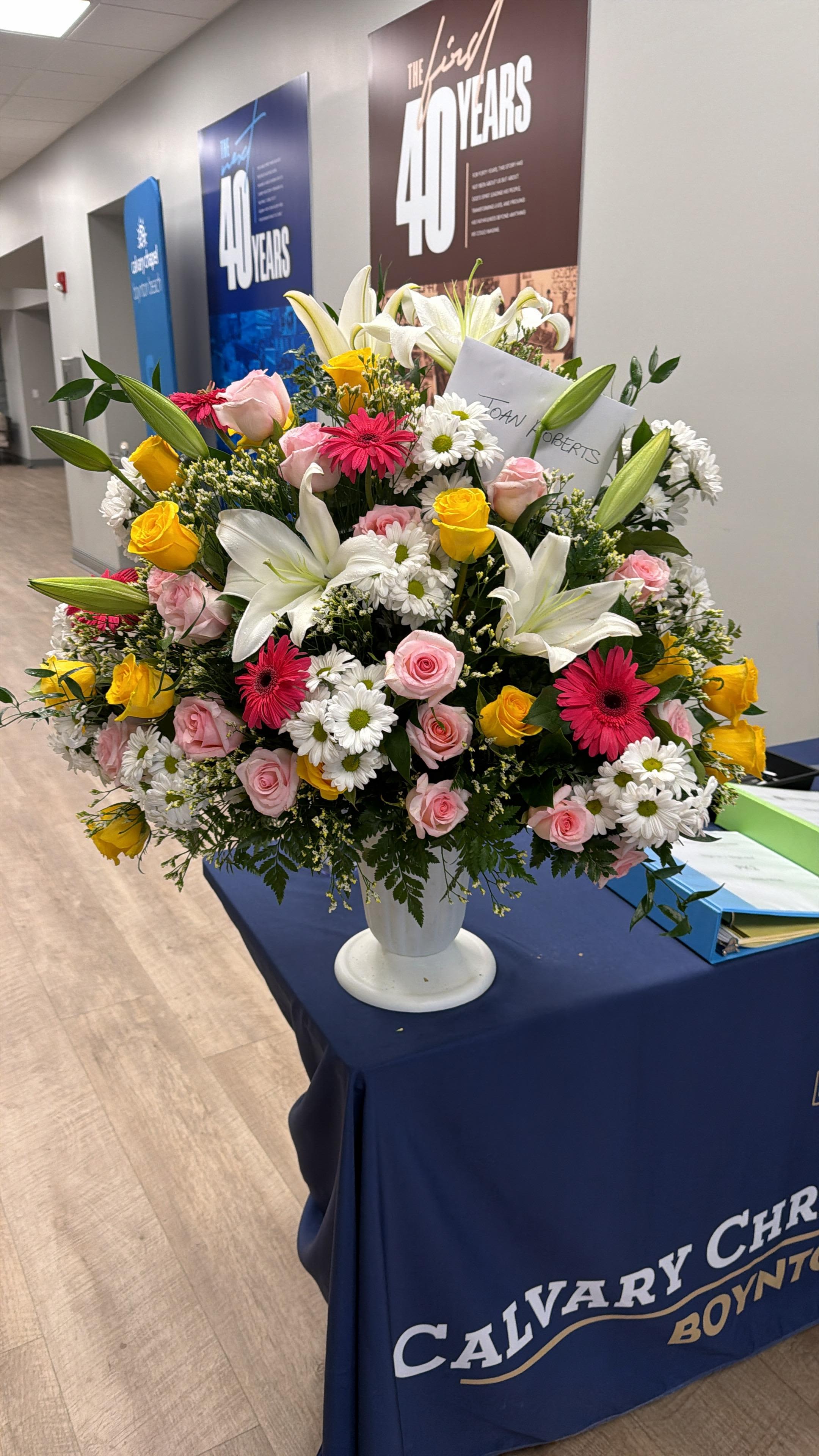 Large mixed flower arrangement in a white pedestal vase
