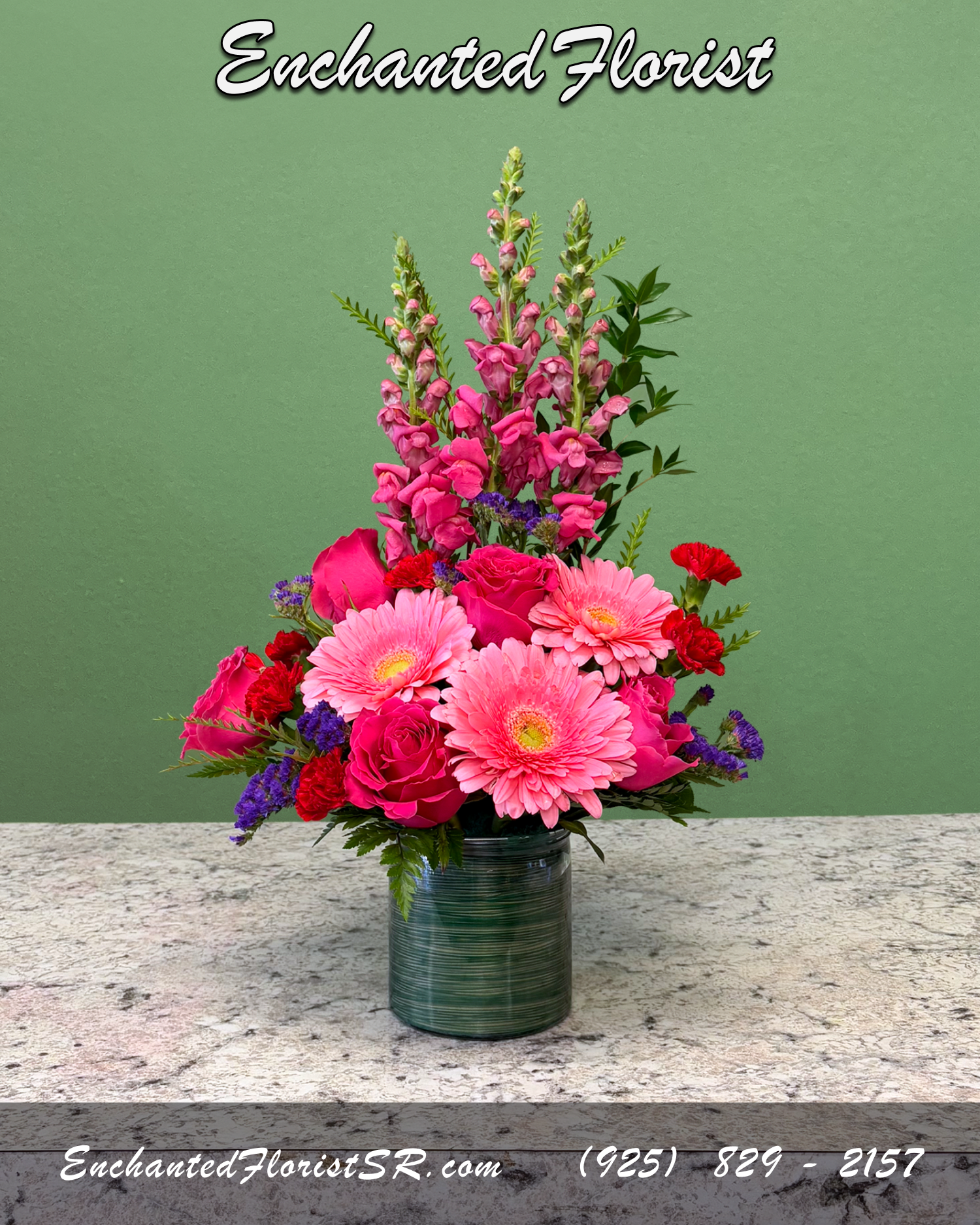 Tall pink floral arrangement with gerbera daisies, roses, and snapdragons in a green glass vase