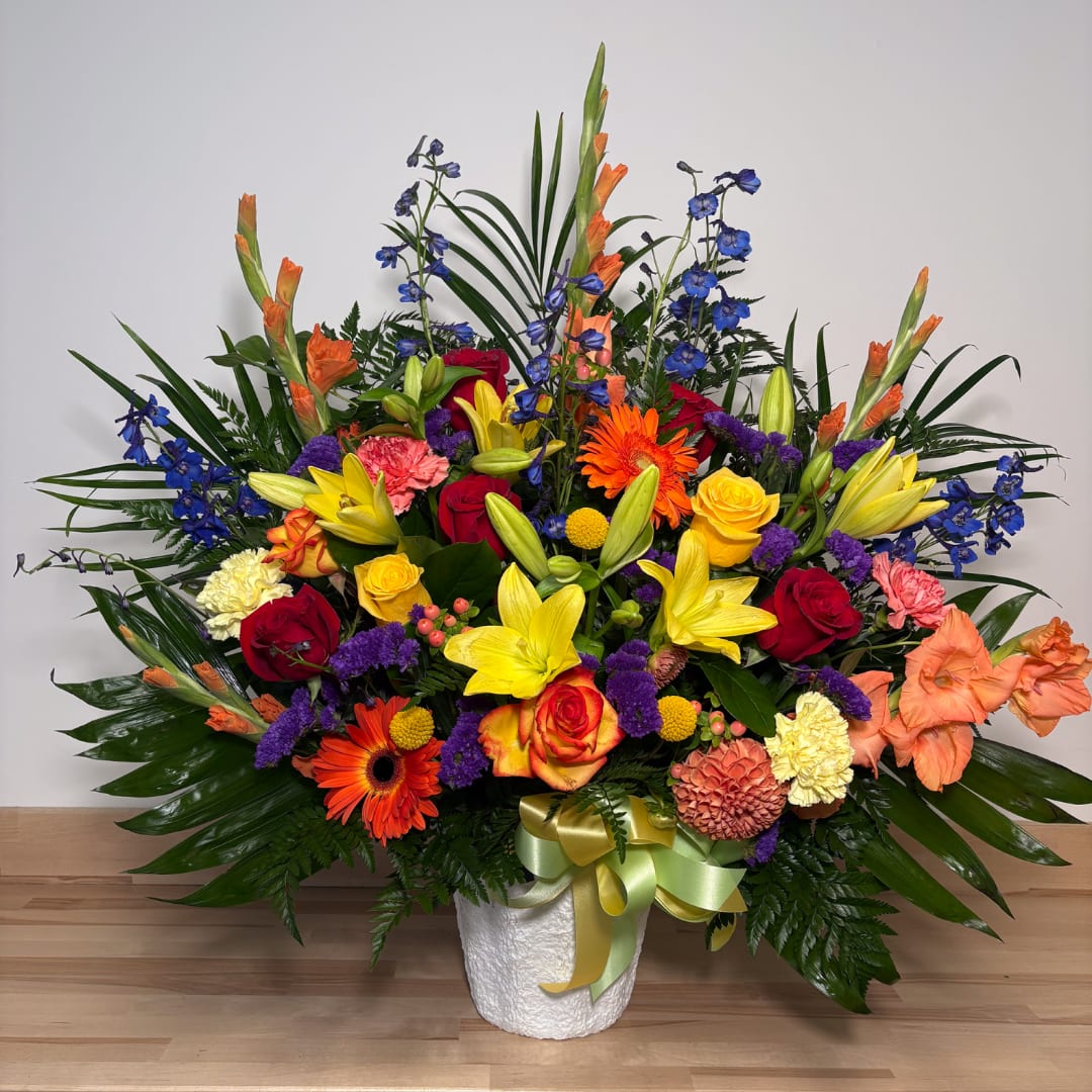 Colorful mixed flower arrangement in a white vase with a ribbon