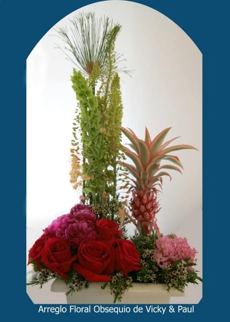Tall tropical floral arrangement with red roses and a pineapple