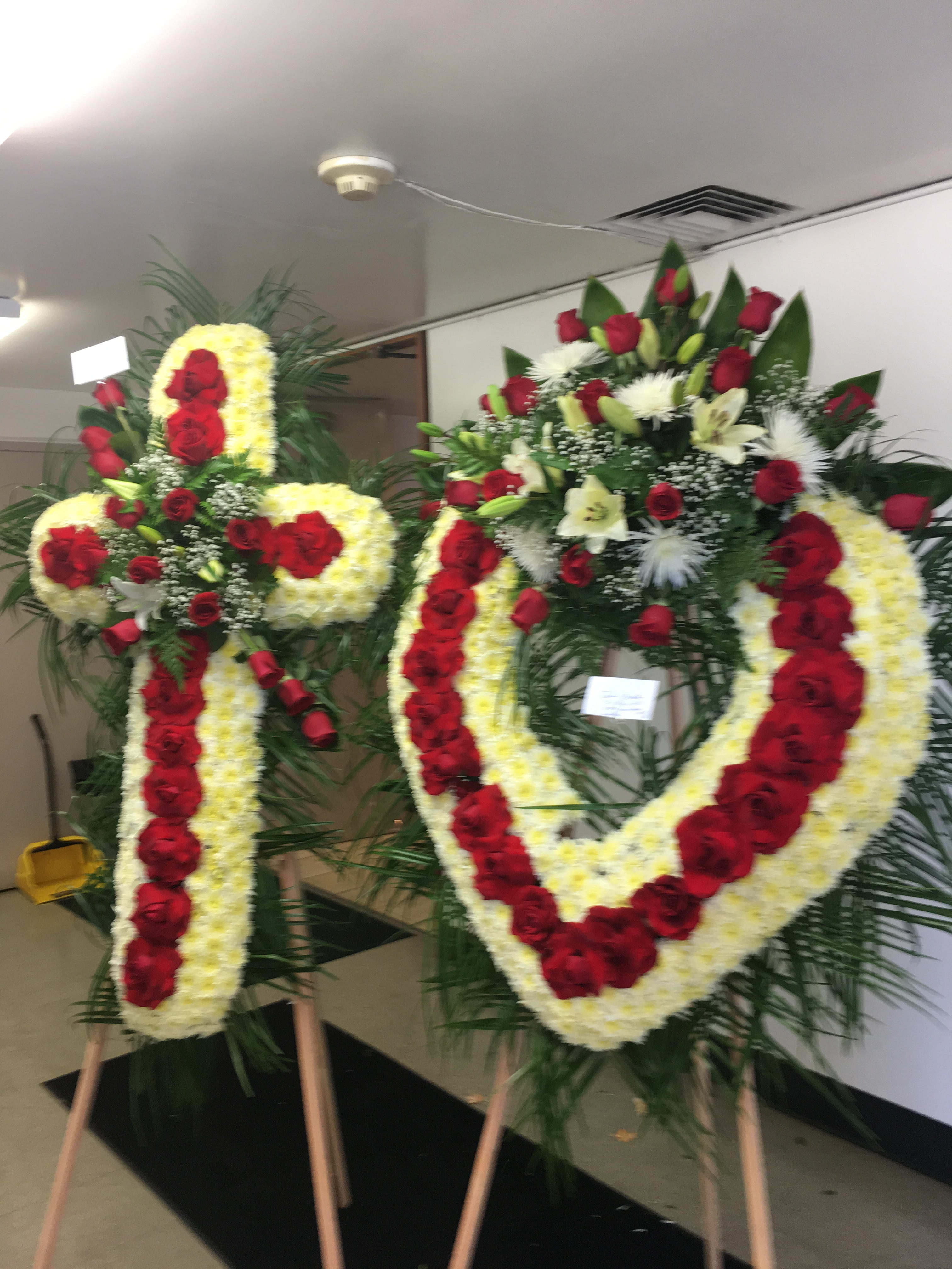 Two large floral funeral wreaths on easels with red and white flowers