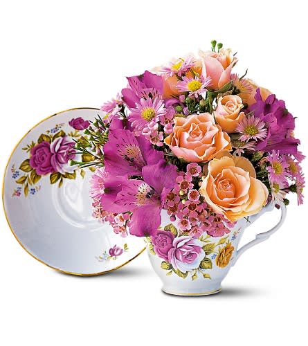 Pink and peach flowers arranged in a floral teacup with matching saucer