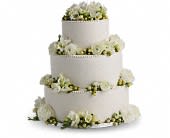 Four-tier white wedding cake with white flowers around each layer