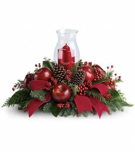 Red candle in a glass hurricane surrounded by apples, pinecones, and ribbon