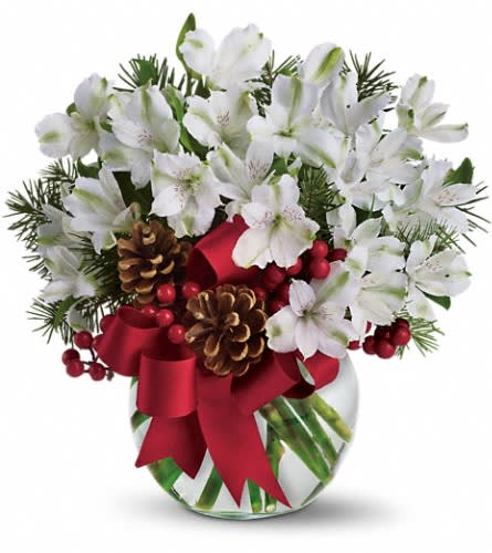 White flowers in a glass vase with red ribbon, pinecones, and berries