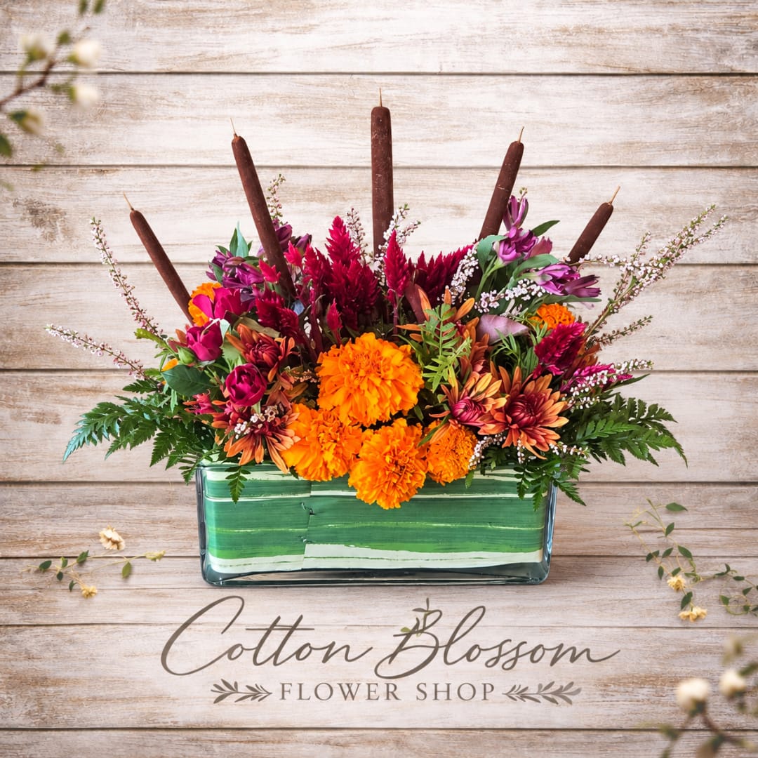 Bright orange and magenta flowers in a rectangular glass vase with candles