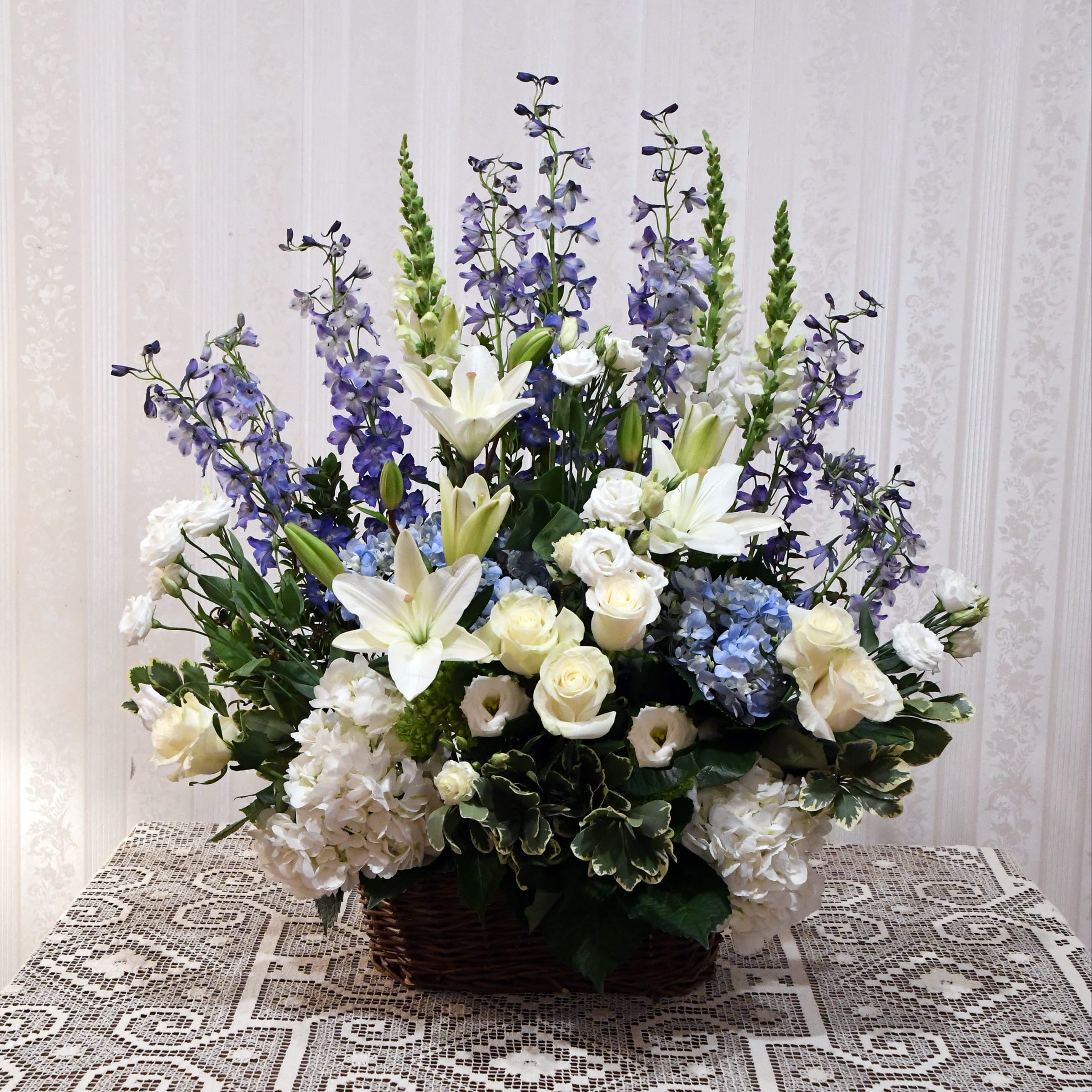 Large basket arrangement with white lilies, roses, hydrangeas, and purple delphinium