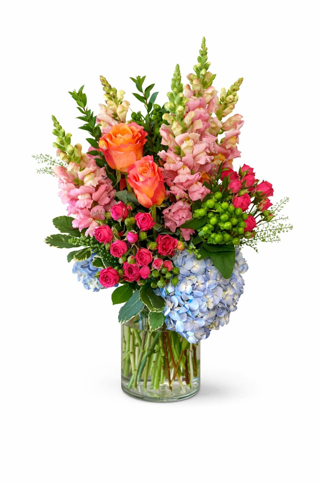 Mixed bouquet of roses, snapdragons, and hydrangeas in a glass vase