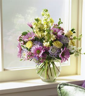 Mixed bouquet of purple and yellow flowers in a clear glass vase