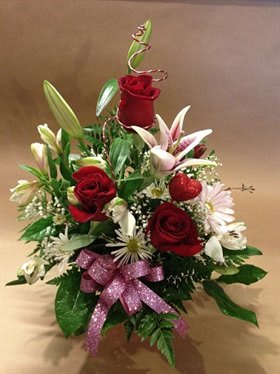Red roses and white lilies arranged with a pink ribbon bow