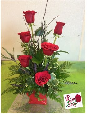 Tall arrangement of red roses in a red container