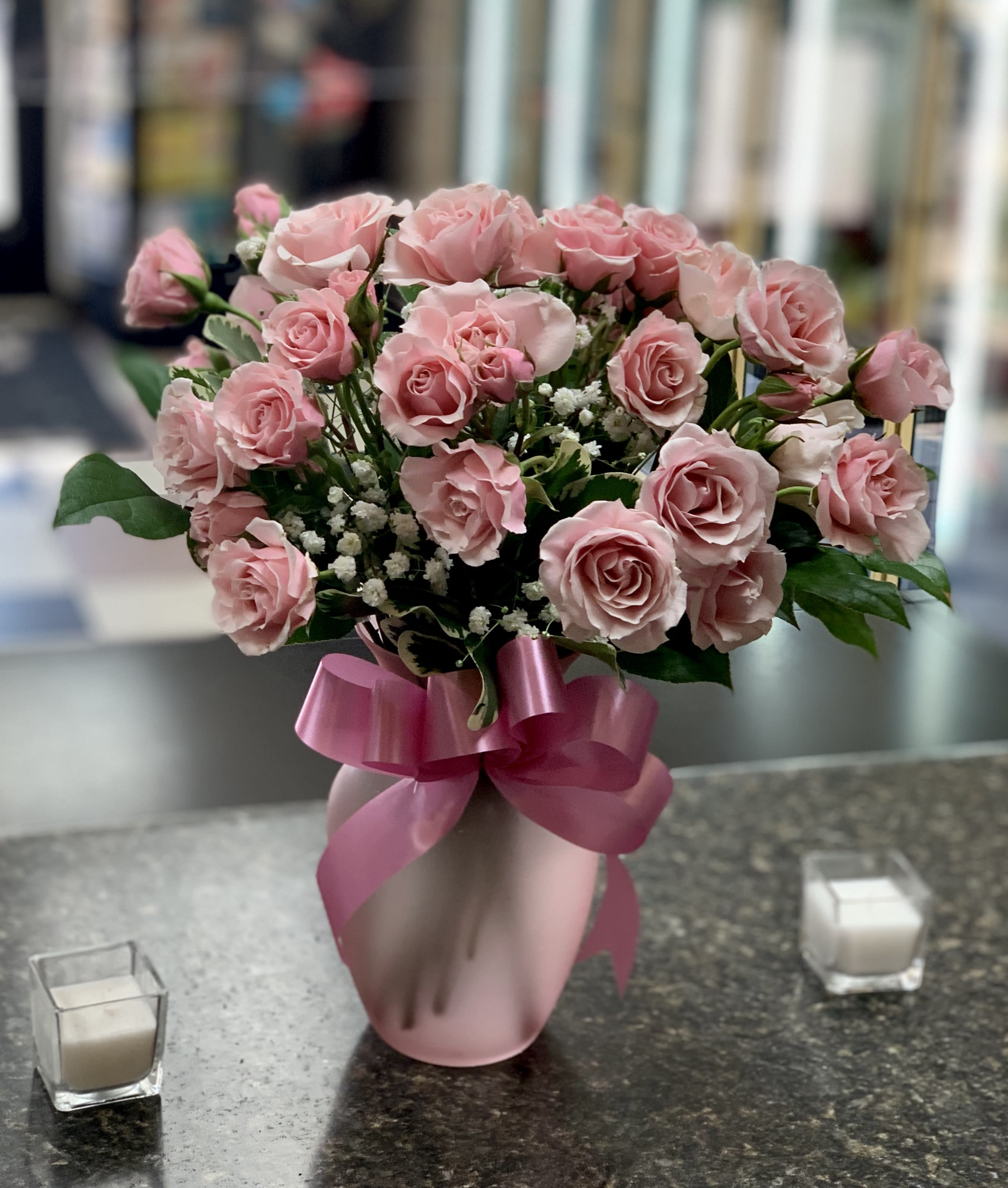 Pink roses arranged in a pink vase with a ribbon bow