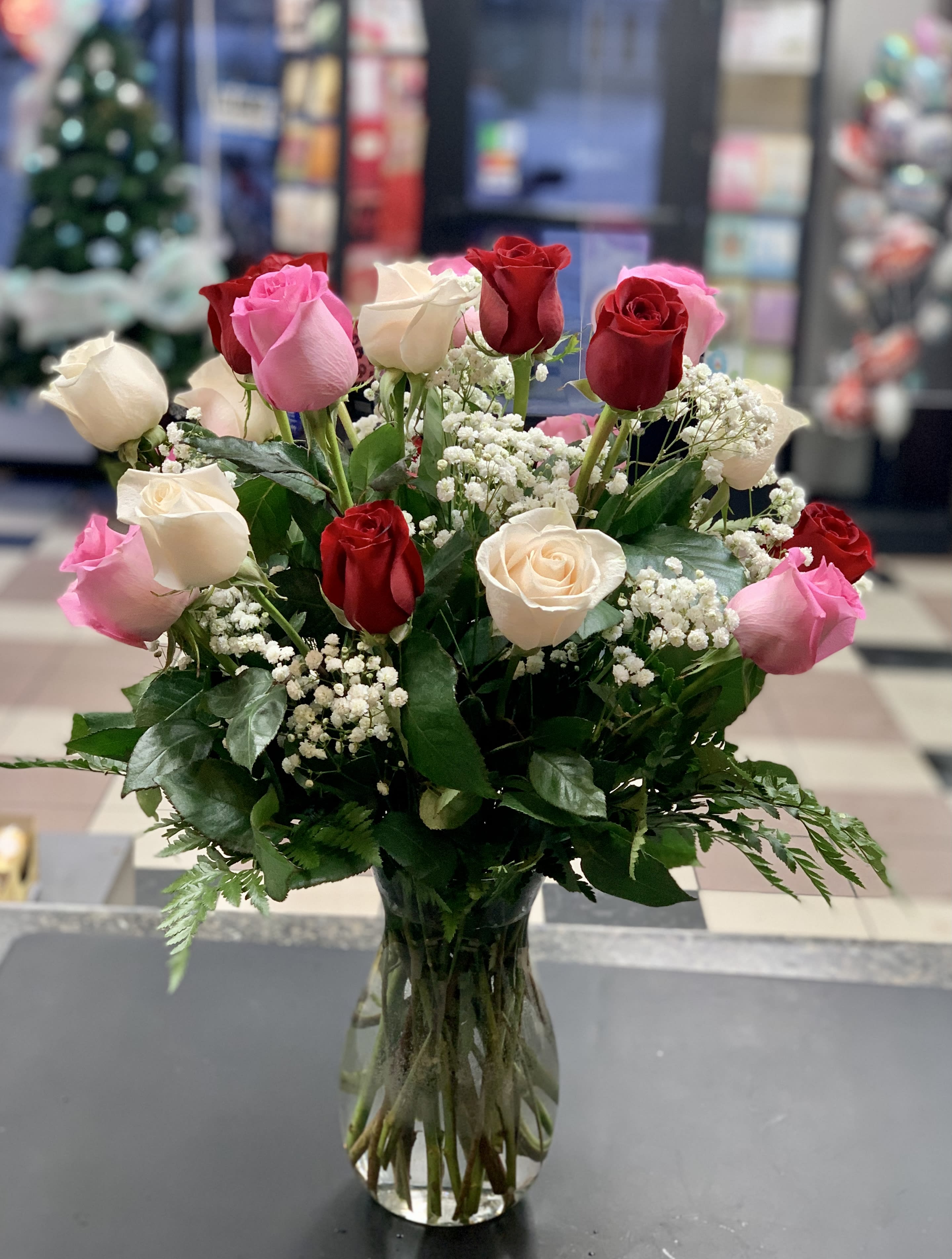 Bouquet of red, pink, and white roses in a clear glass vase