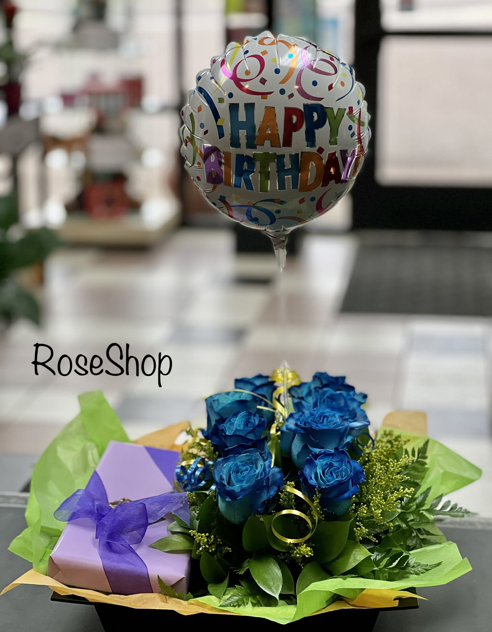 Blue roses with a happy birthday balloon and gift box