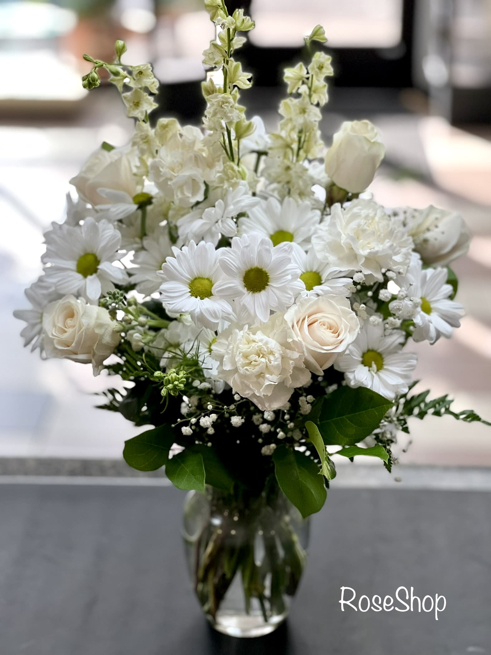 White bouquet of daisies and roses in a clear glass vase