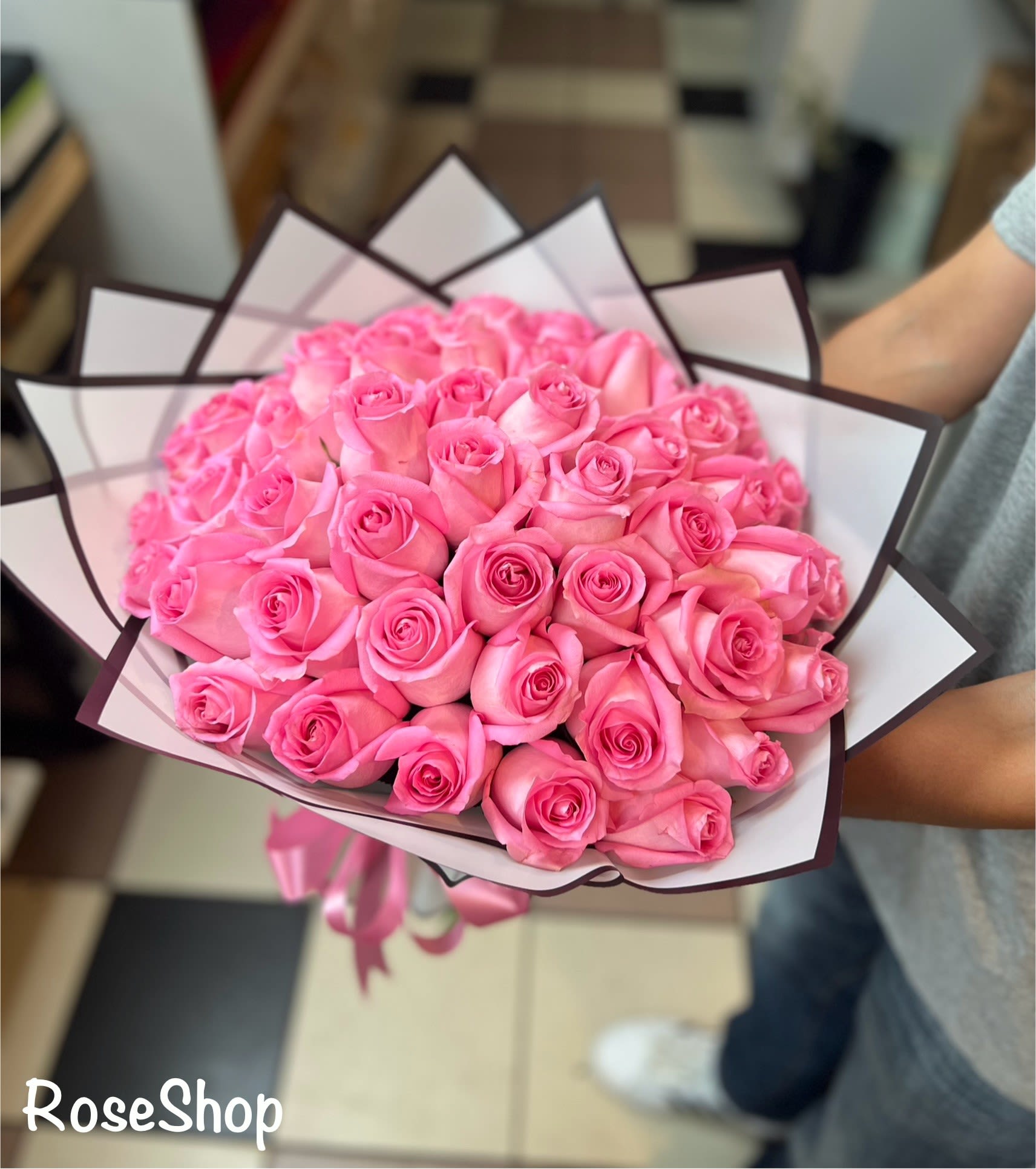 Bouquet of pink roses wrapped in white and dark-edged paper