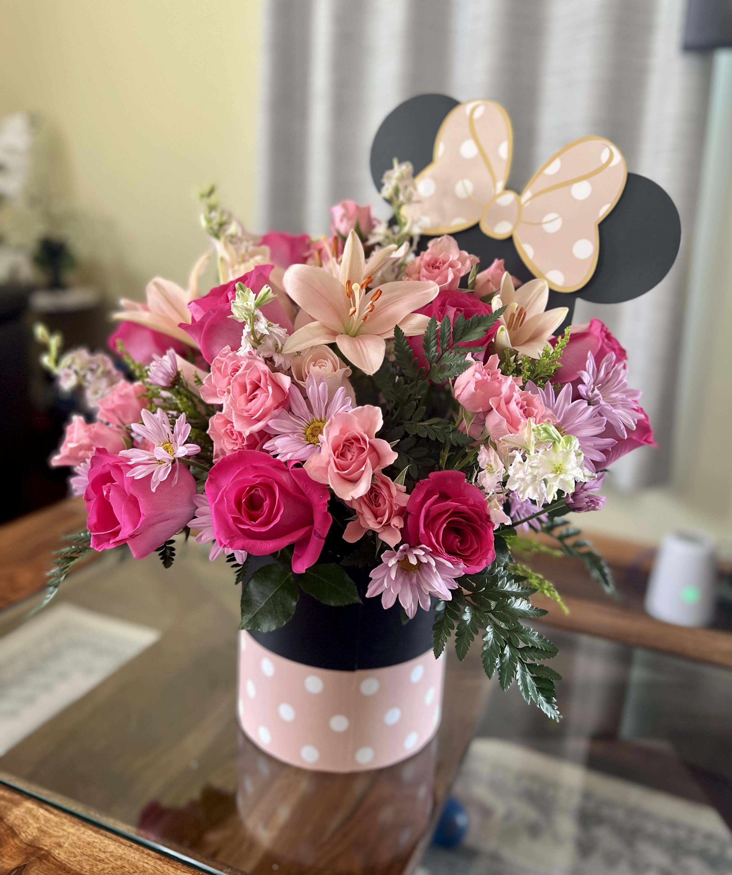 Pink and peach flower arrangement in a polka-dot box with a butterfly topper