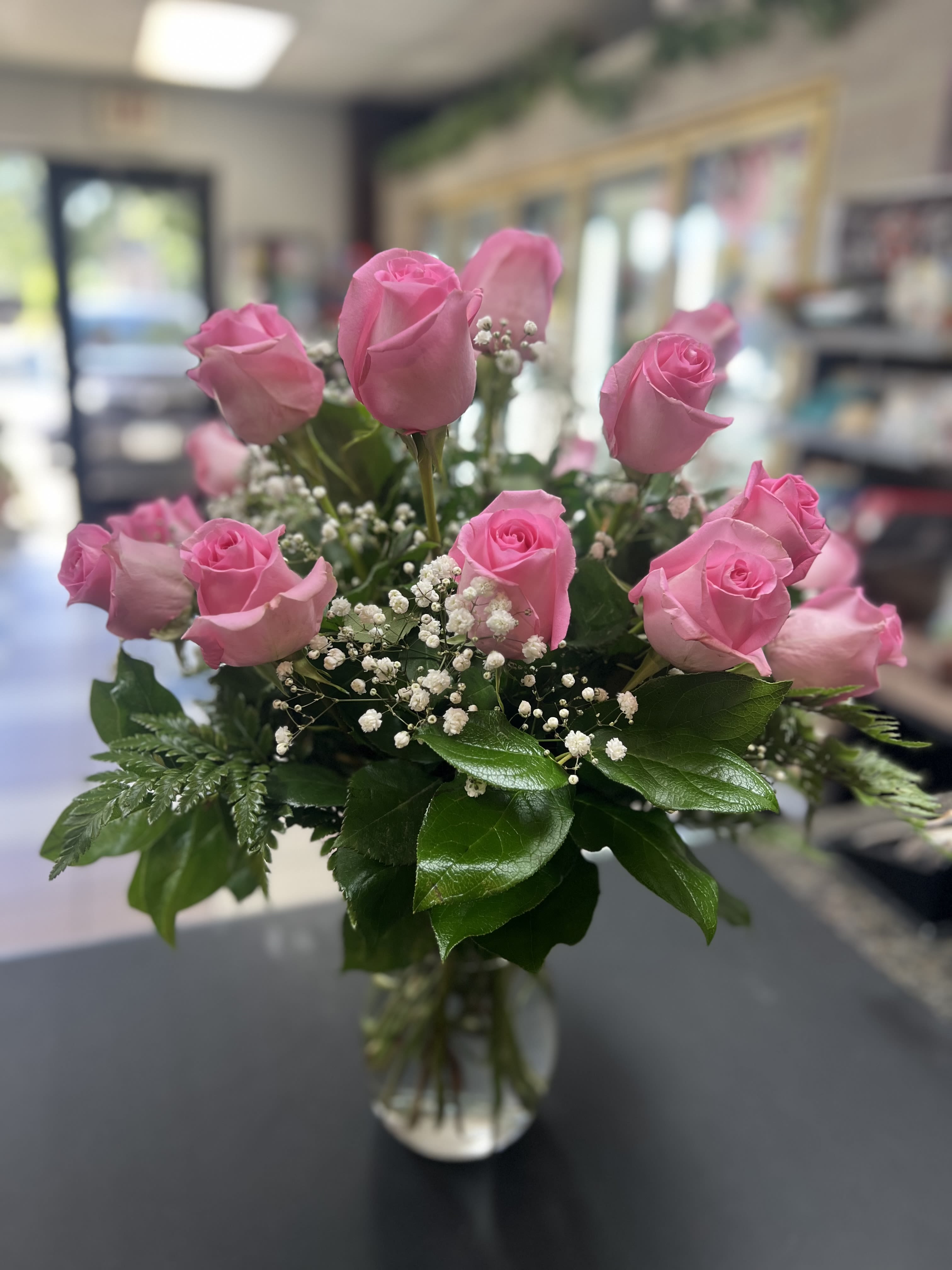 Pink roses arranged in a clear glass vase with baby's breath