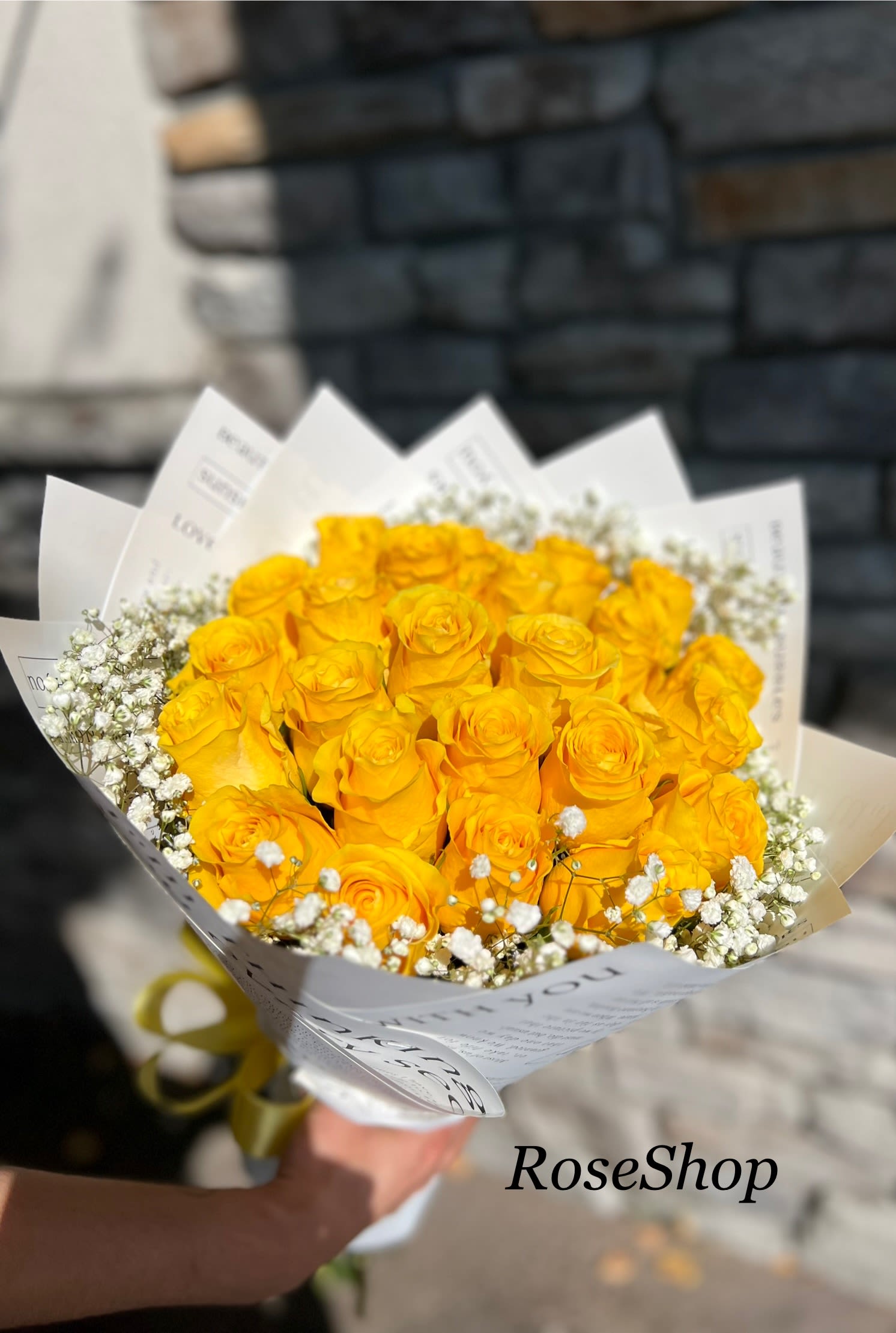 Bouquet of yellow roses with white baby's breath in white paper wrap