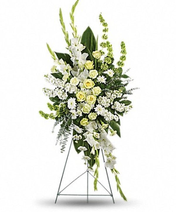 White and pale yellow funeral spray on a metal easel
