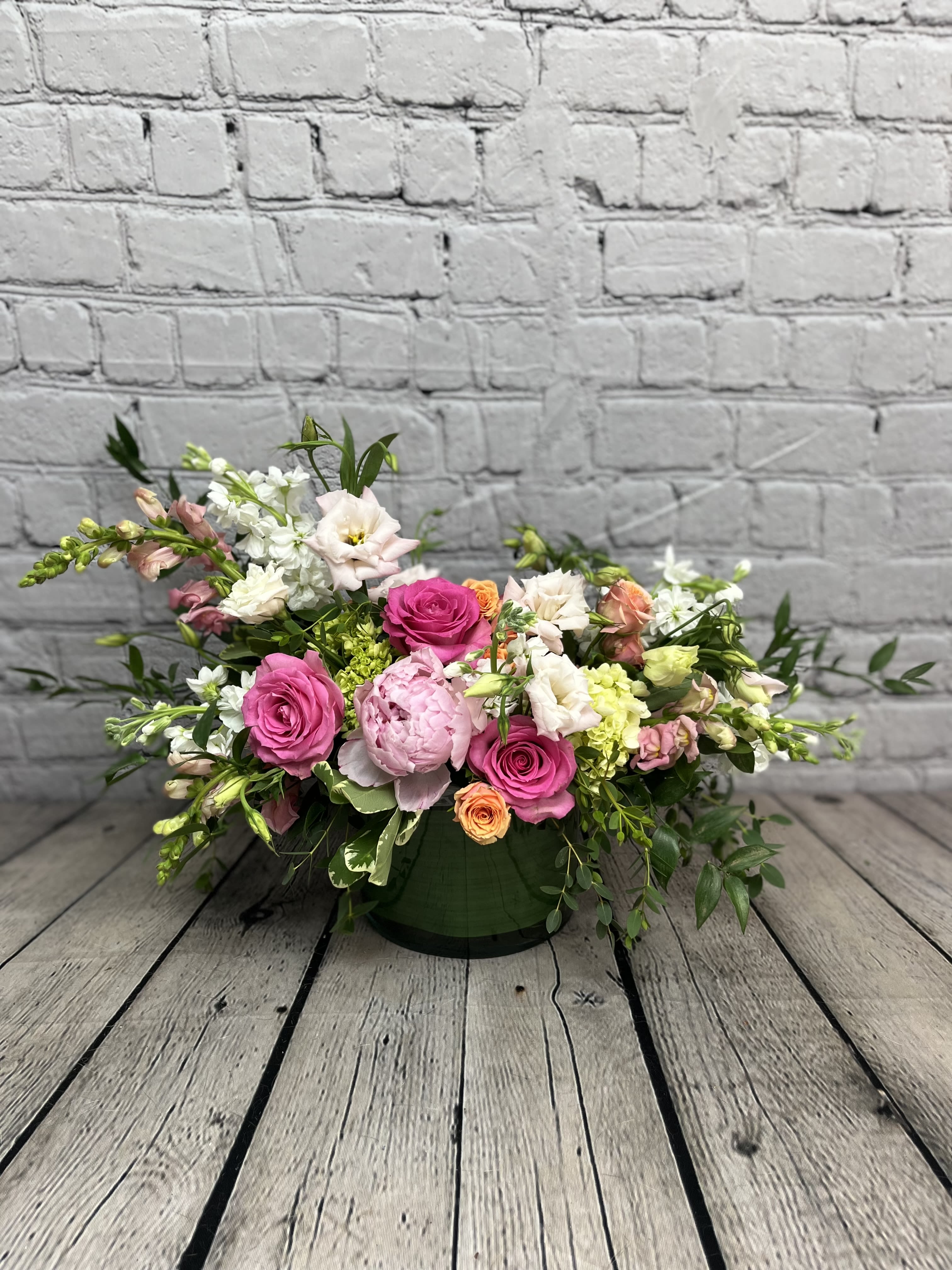 Mixed pink and white floral arrangement in a green container