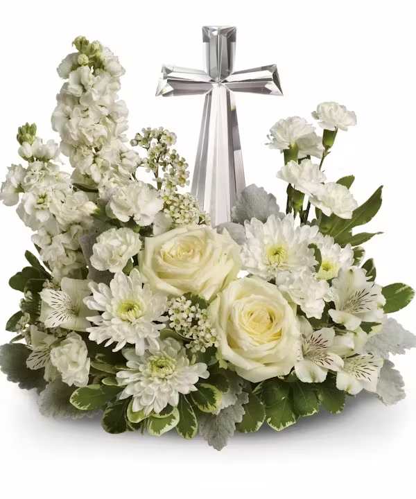 White floral arrangement with roses, daisies, and a silver cross