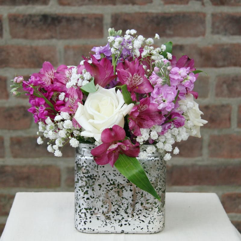 Pink and white flower arrangement in a silver square vase