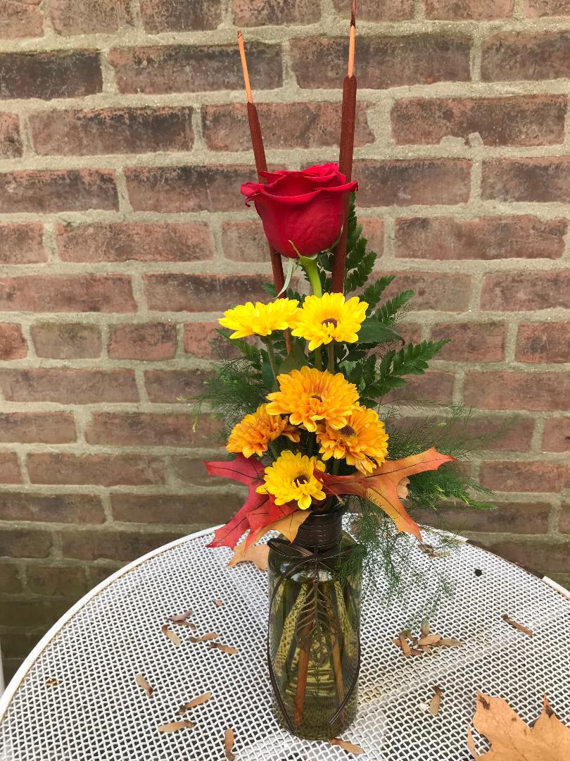 Autumn Leaf Budvase - A soft green glass vase with a metal leaf detail in front.  Filled with seasonal chrysanthemums, a red rose, and cattails