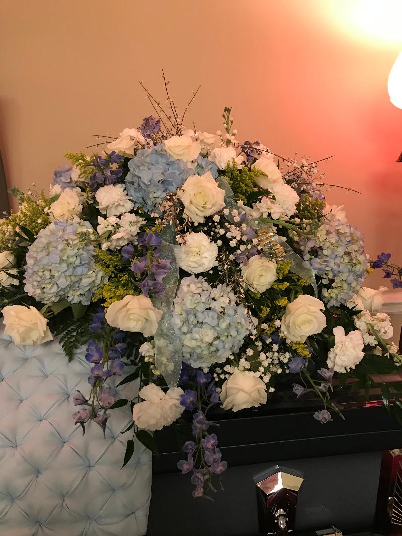 Large floral arrangement with white roses, blue hydrangeas, and purple flowers