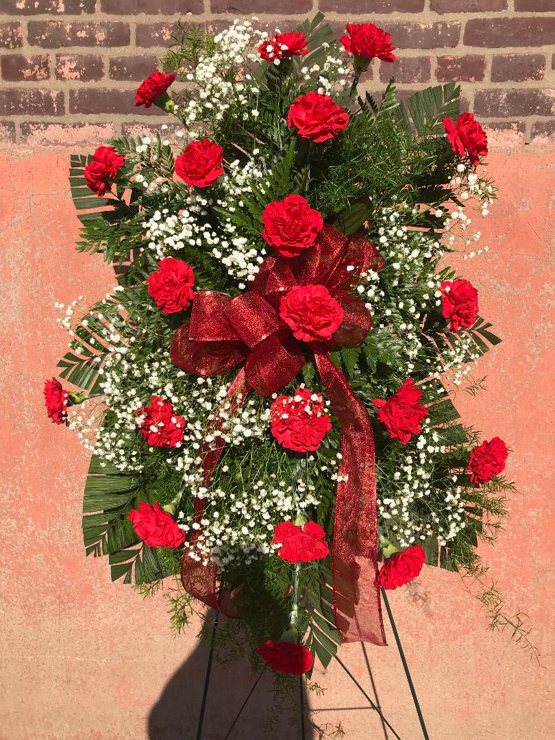 Standing spray of red carnations with white baby's breath and a red ribbon