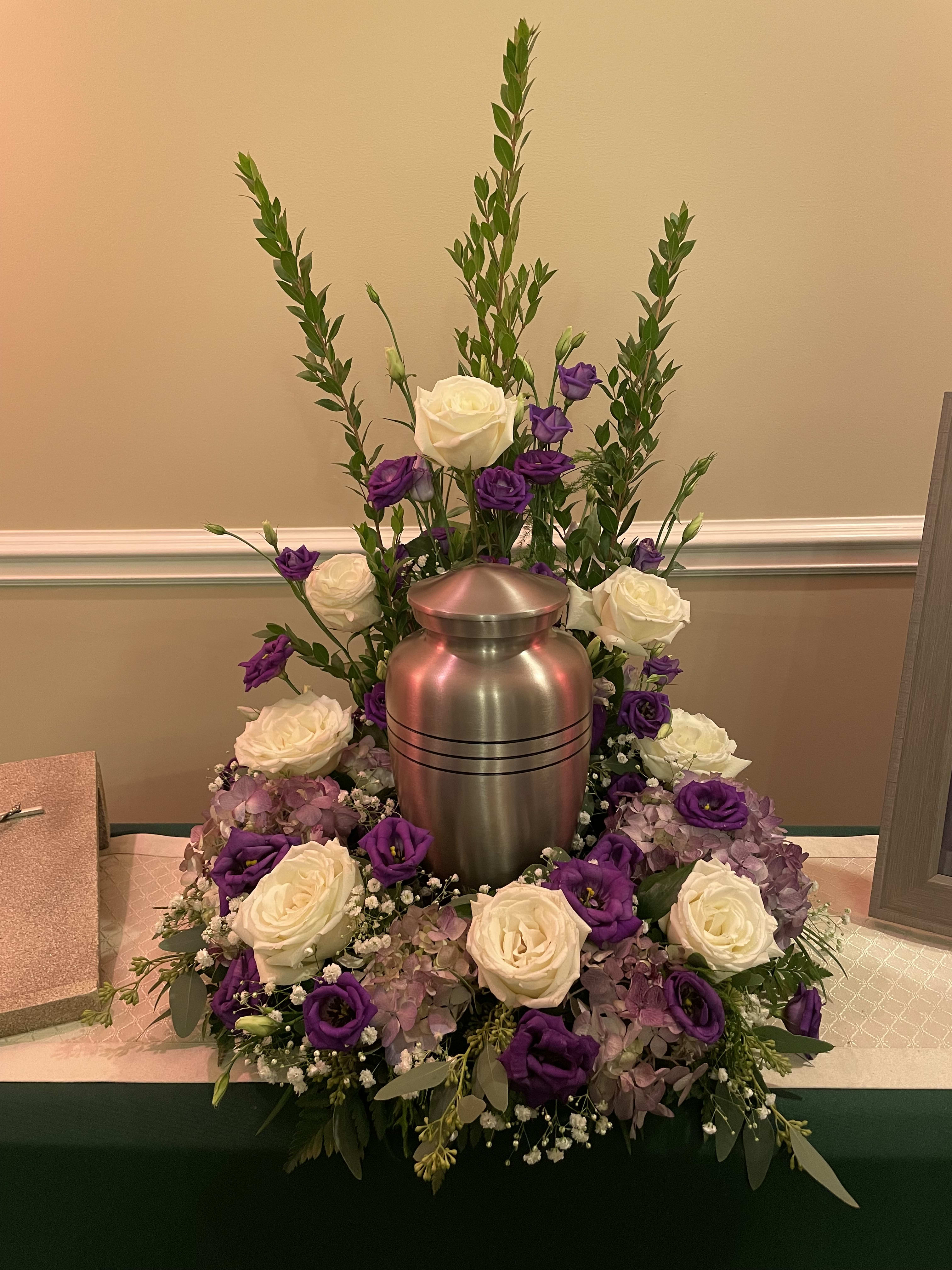 White and purple roses arranged around a silver urn