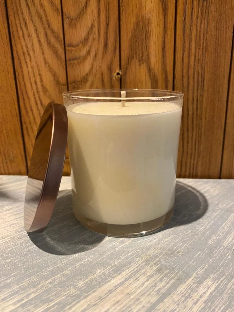 White candle in a clear glass jar with a metal lid