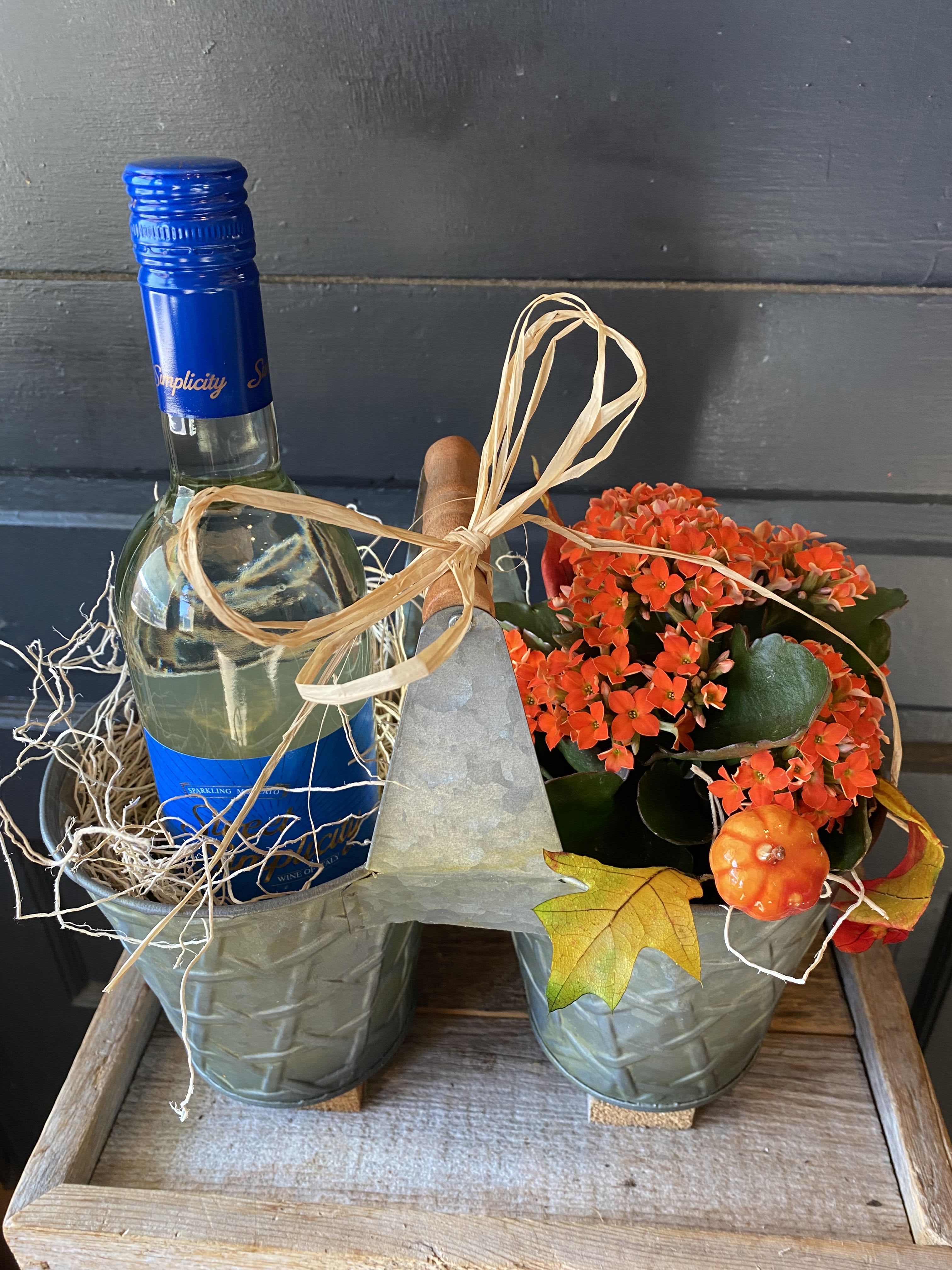 Gift basket with a wine bottle and orange potted flowers